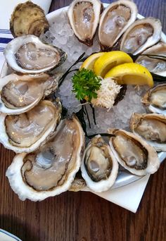 an oyster platter with lemon wedges and parsley on the half - shell