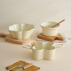 three white dishes with wooden utensils on a table