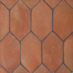 an orange brick wall with hexagonal tiles on the top and bottom, in different colors