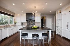 a large kitchen with white cabinets and black counter tops, an island in the middle