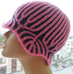 a mannequin head wearing a pink and black knitted hat on top of a window sill