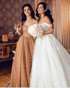 two women in dresses standing next to each other and one is holding a flower bouquet