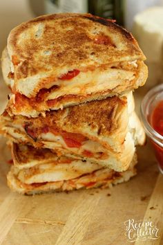 three grilled cheese sandwiches stacked on top of each other next to ketchup