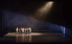 a group of people standing on top of a stage under spotlights in the dark