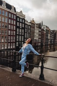 a woman leaning on a railing in front of some buildings