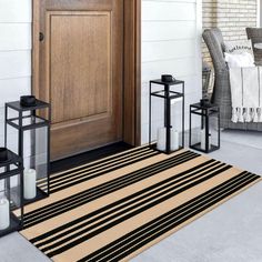 the front door is decorated with lanterns, candles and an area rug that has stripes on it