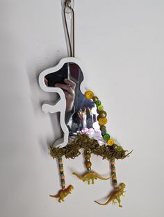 an animal ornament hanging from a hook on a wall with flowers and plants