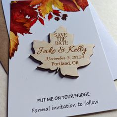 a wooden save the date card with a maple leaf on it and text that reads, put me on your fridge for formal invitation to follow