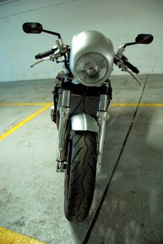 a motorcycle parked in a parking lot next to a yellow line on the ground with it's lights on