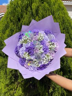 someone holding a bouquet of purple flowers in their left hand and the other hand is reaching for it