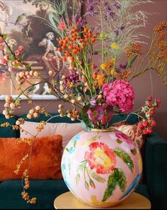 a vase filled with flowers sitting on top of a table next to a green couch