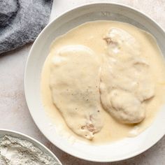 two white bowls filled with food on top of a marble counter next to a gray towel