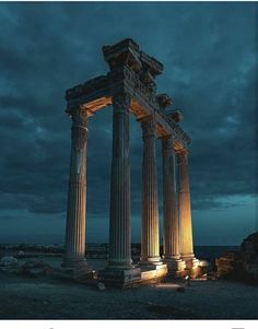 an old building with columns lit up in the dark sky at night, and there is no image to describe