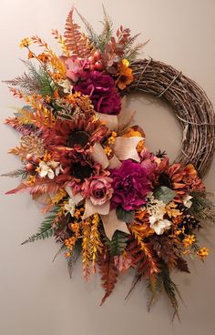 a wreath with flowers and leaves hanging on the wall