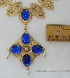 Wear a piece of history with this "Mary, Queen of Scots" movie-inspired reproduction Tudor necklace. Crafted with ornate gold-tone filigrees and captivating acrylic cabochons, this regal accessory adds unique glamor to any look. Necklace length is 17-18", with a 2-3" extender attached. Longer and shorter lengths available upon request, message me with your desired length. Vintage Baroque Jewelry With Historical Design, Costume Gold Metal Jewelry, Elegant Gold Costume Jewelry, Elegant Gold Jewelry For Costume, Vintage Filigree Baroque Jewelry, Vintage Filigree Baroque Necklace, Collectible Gold Baroque Jewelry, Ornate Gold Necklace With Cabochon, Medieval Necklace