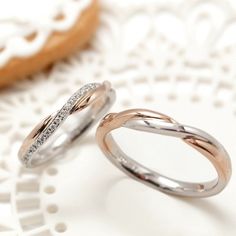 two wedding rings sitting next to each other on a doily with cookies in the background