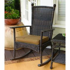 two wicker rocking chairs sitting on a porch next to a potted planter