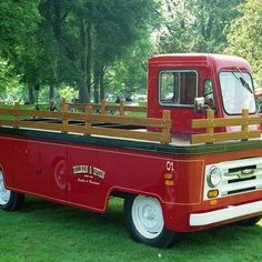 an old red truck is parked in the grass