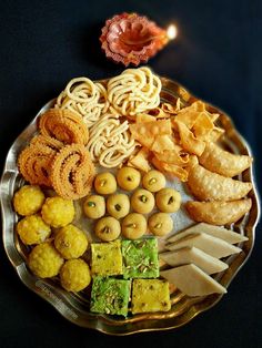 an assortment of food on a plate with a lit candle in the background, including crackers and cookies