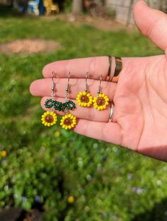 a person is holding three small yellow flowers in their hand, and they are attached to tiny rings