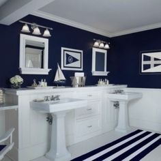 a bathroom with blue and white walls, striped rugs and pictures on the wall