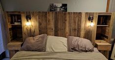 a bed made out of pallet wood with two lights on the headboard and pillows