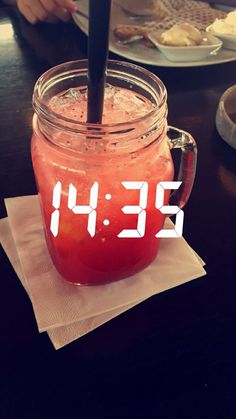 a glass jar filled with liquid sitting on top of a table next to a clock