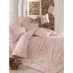 a bed with pink comforters and pillows in a room next to a brick wall