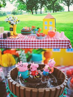 peppa pig birthday party with cake, decorations and table cloth on the grass outside