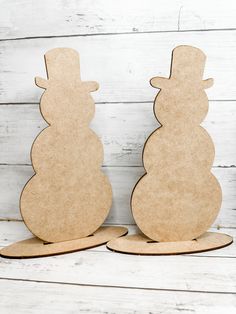 two wooden snowmen standing next to each other on top of a white wood floor