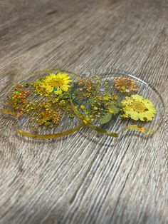 some yellow flowers are sitting in a glass dish on a wooden table and it looks like they have fallen apart