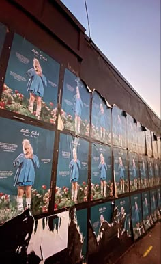 a wall covered in pictures of women's soccer uniforms on display at the side of a building