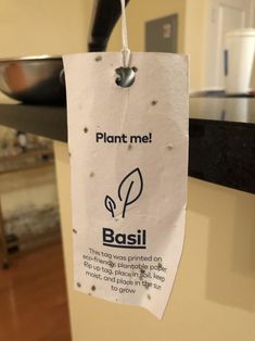 a plant me sign hanging from a kitchen counter