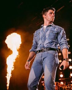 a man standing on top of a stage with his hands in his pockets as he sings