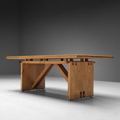 a wooden table sitting on top of a white floor next to a gray wall in an empty room