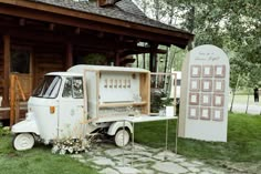 an old white truck is parked in front of a wooden building with flowers on it