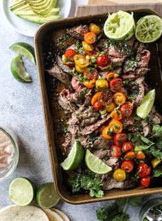 a tray filled with meat, tomatoes and avocado slices on top of a table