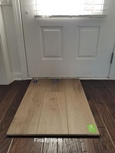 a wooden floor mat sitting in front of a white door