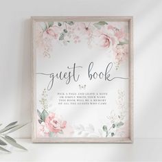 the guest book sign with pink flowers and greenery is displayed in front of a white wall