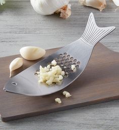 garlic being gratered on a cutting board next to garlic cloves and garlic florets