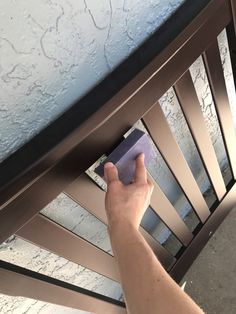 a person is cleaning the bottom of a metal bed frame with a blue cloth on it