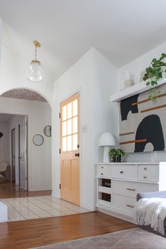 a living room with white walls and wooden floors is pictured in this image from the entryway