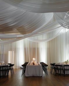 a banquet hall with white draping and wooden floors