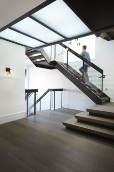 a man is walking up the stairs in an empty room with wood floors and white walls