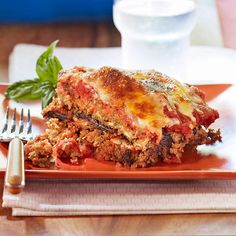 a piece of lasagna on an orange plate with a fork