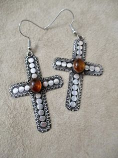 These vintage 70s earrings are set with beautiful amber colored stones in bezels.  The sterling silver crosses measure 1 7/8" high and 1 1/8" across and dangle 2 1/2" down. The ear wires are not sterling, but hypoallergenic metal.  The original ear wires were damaged. This pair of sterling cross earrings is gorgeous! If you need more info or photos, I am happy to help :) 70s Earrings, Silver Cross Earrings, Goth Earrings, Colored Stones, Gothic Beauty, Amber Stone, Star Bracelet, Unique Birthday Gifts, Cross Earrings