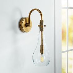 a wall light with a clear glass bulb hanging from it's side on a white wall