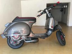 a motor scooter parked in a room with tile flooring and white walls