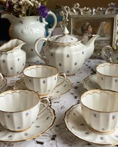 a table topped with lots of white and gold cups and saucers on top of a table