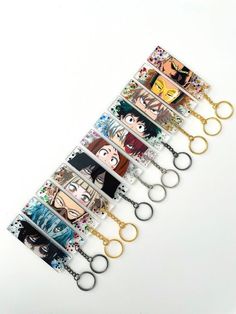 several anime key chains are lined up on a white surface